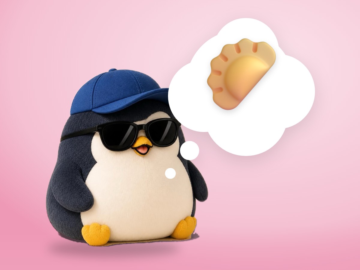 An embroidered felt penguin in a bright rainbow knit hat next to a steamed shumai with a green pea on top