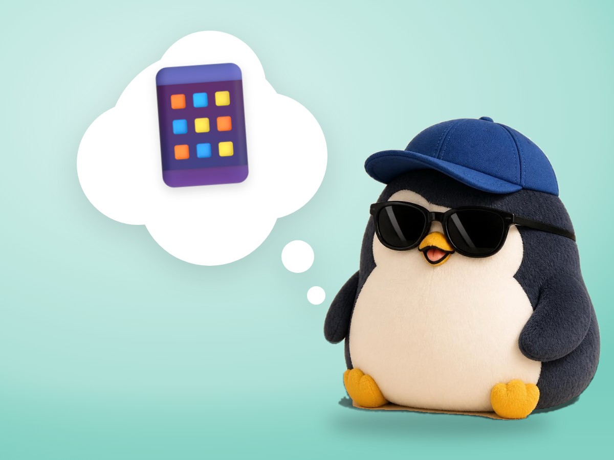 A hand-embroidered felt penguin smiling at a cafe table with a smartphone lying face down