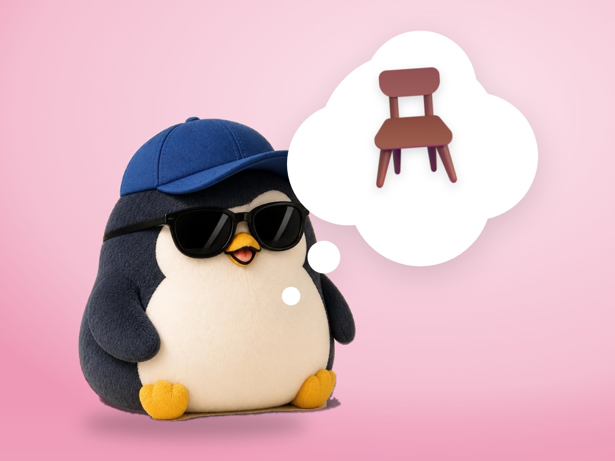 A brushed mohair penguin standing up from a small writing desk next to a notebook and a simple kitchen timer