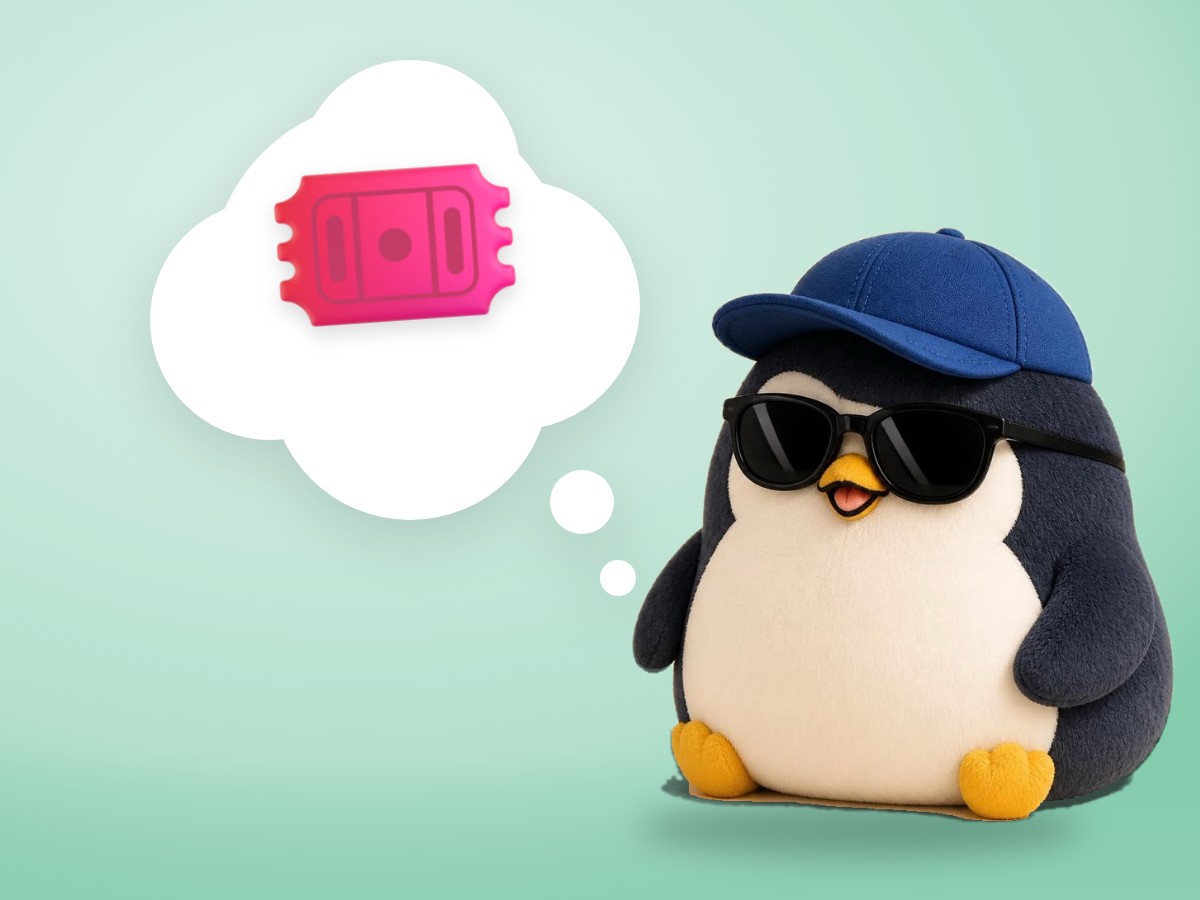 A plush corduroy and felt penguin holding a paper admission ticket in front of a small striped ticket booth